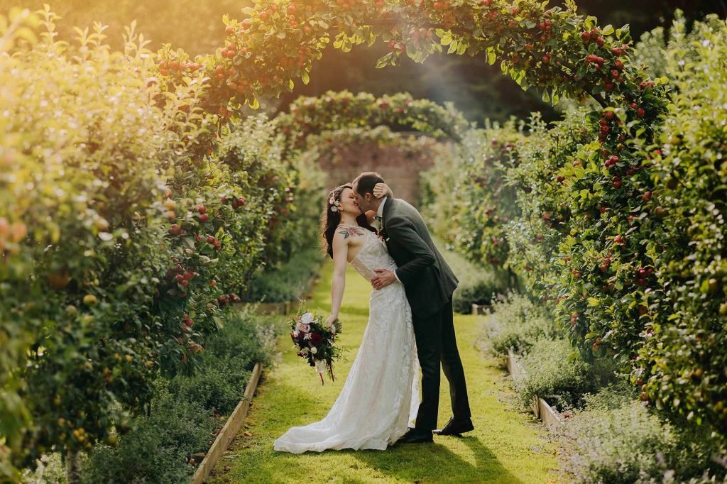 Stunning Garden Wedding Venues in the UK Bride and groom kiss on the apple espalier at Homme House.jpg 5