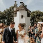 Homme House Bride and groom walk down wedding aisle with Homme House Summerhouse in the background.jpg 2