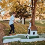Young guest playing crazy golf hole run by Putt Putt Golf